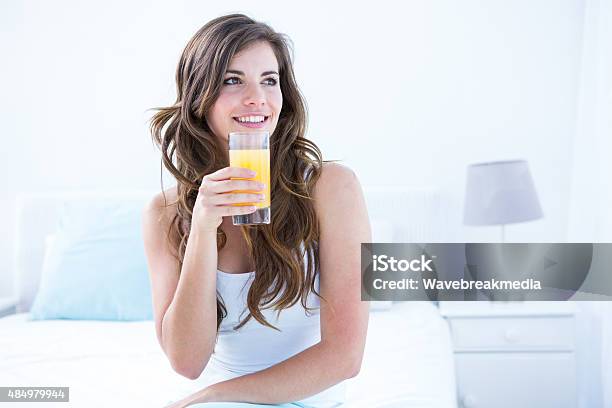 Thoughtful Brunette Drinking A Glass Of Orange Juice Stock Photo - Download Image Now