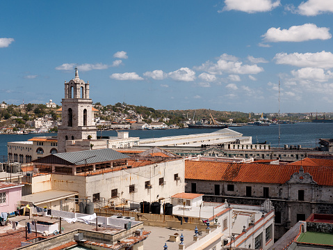 Havana, Cuba - March 13, 2010: Roof top view over the city with a church tower and dome in the middle distance and the  bay and harbour  in the background