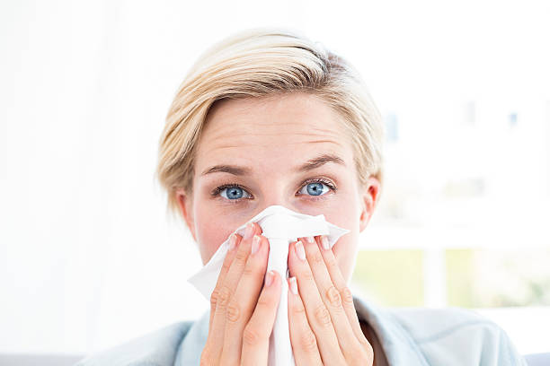 istock Sick blonde woman blowing her nose 484988316