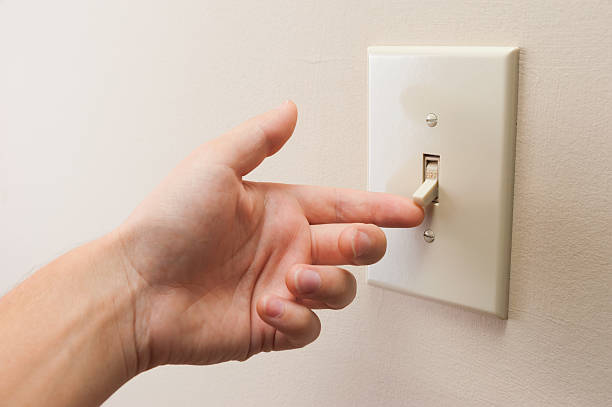hand turning wall light switch off - startknop stockfoto's en -beelden