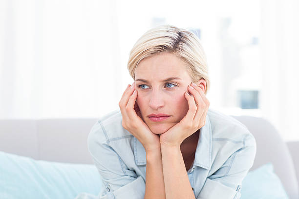 istock Thoughtful blonde woman sitting on the couch 484993562
