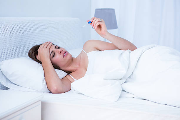 istock Sick woman looking at her thermometer 484994004
