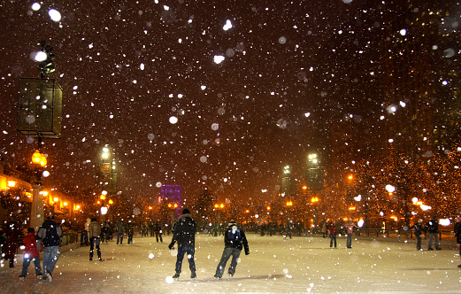 People enjoying ice skating during snowy night in Chicago
