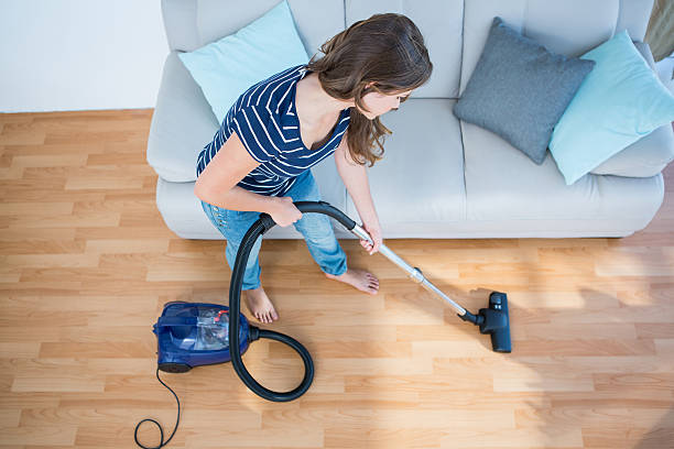 istock Woman using vacuum cleaner on wooden floor 485005502