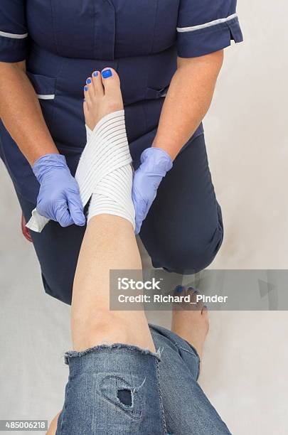 Ladies Injured Ankle Being Dressed By A Nurse Stock Photo - Download Image Now - 2015, Adult, Ankle