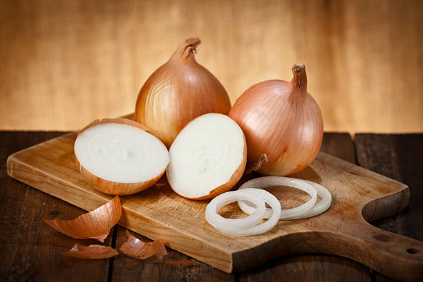istock Gold onions on a wooden cutting board 485007572