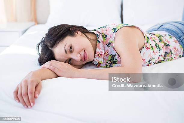 Pretty Brunette Looking At Camera And Lying On Bed Stock Photo - Download Image Now - 2015, 30-34 Years, 30-39 Years