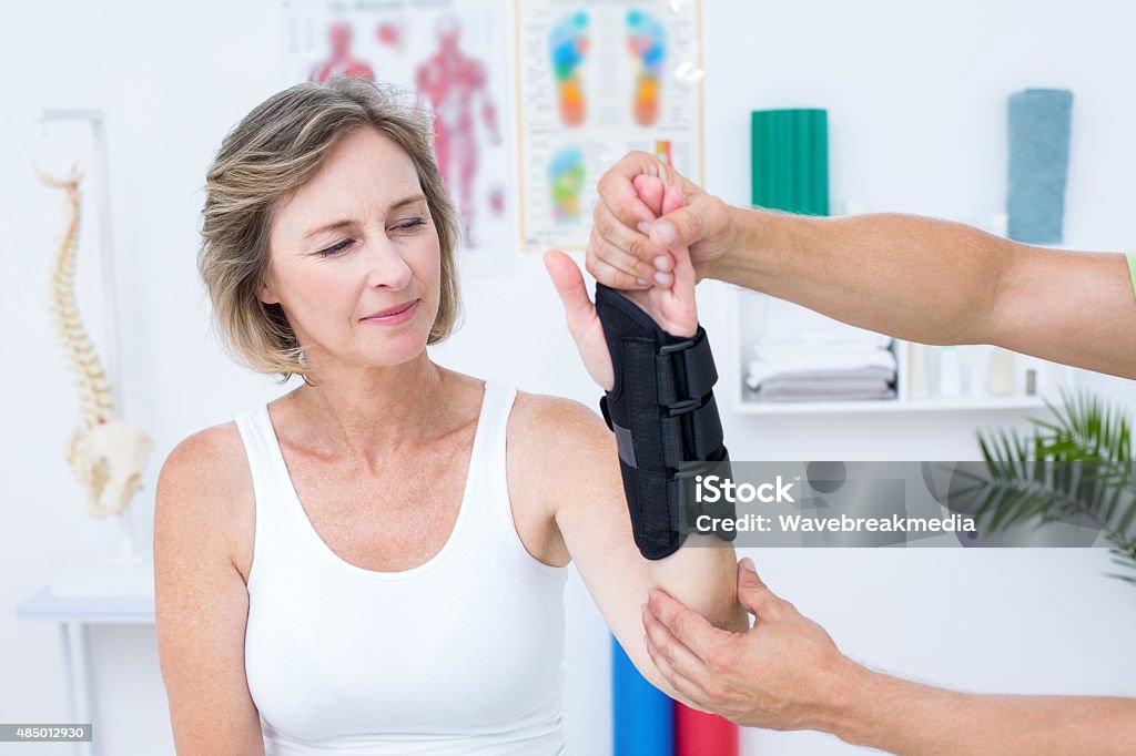 Doctor examining his patients wrist Doctor examining his patients wrist in medical office Orthopaedic Brace Stock Photo