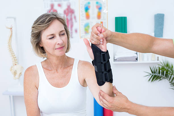 Doctor examining his patients wrist Doctor examining his patients wrist in medical office wrist stock pictures, royalty-free photos & images