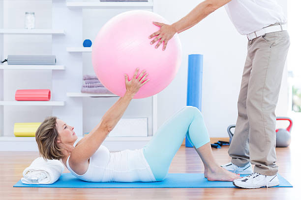 istock Therapist helping his patient with exercise ball 485013350