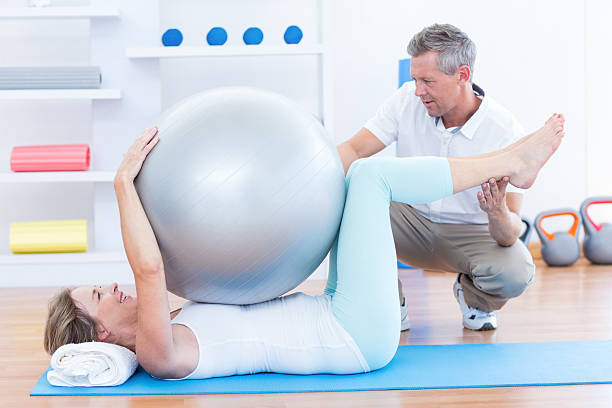 istock Therapist helping his patient with exercise ball 485013358