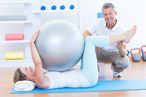 istock Therapist helping his patient with exercise ball 485013374