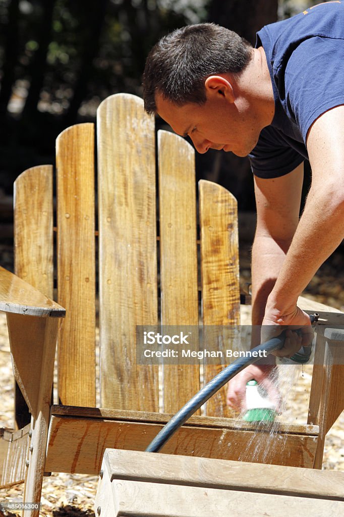 Restoration: Teak wood chair - man cleaning A man cleaning his teak wood chair he has just restored and refinished. 2015 Stock Photo