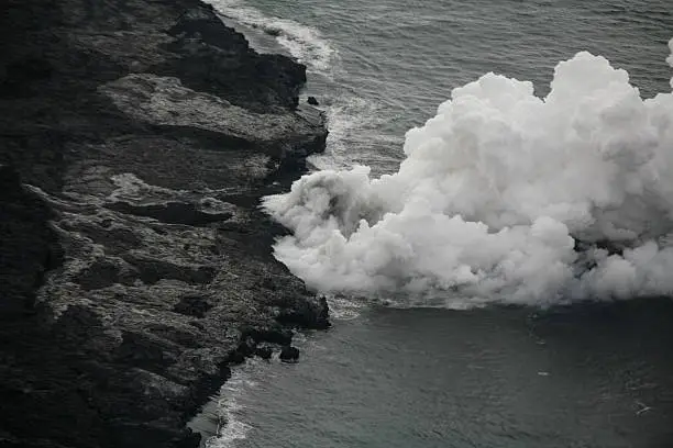 Aerial view of Hawaiian volcanic activity flowing into the Pacific Ocean.
