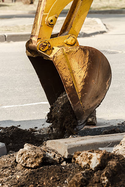 istock Yellow excavator is scooping deep trench on land under asphalt 485017939