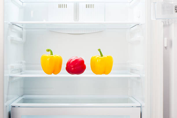 istock Two yellow with one red peppers on shelf of refrigerator 485018972