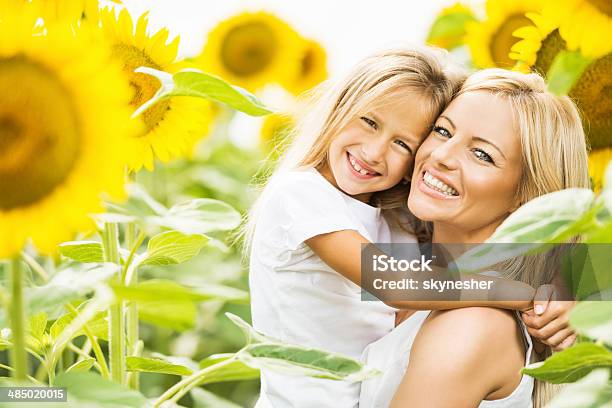 Smiling Mother And Daughter Among Sunflowers Stock Photo - Download Image Now - Mother, Sunflower, 30-39 Years