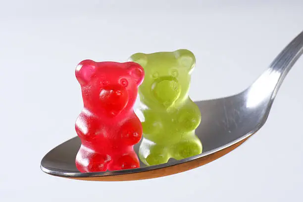 two gummy bears standing on metal spoon