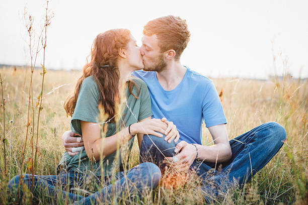 premier amour: jeune couple embrasser dans la prairie - pre teen boy photos et images de collection