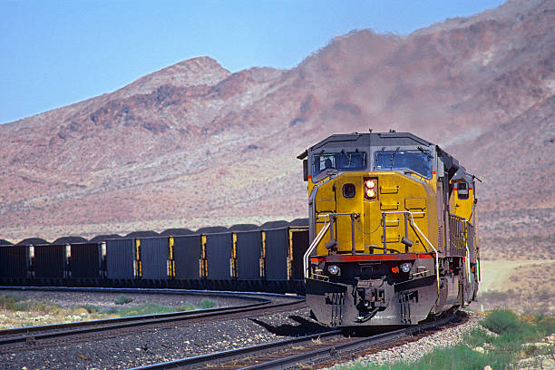 Loaded coal train with mountain background Two powerful diesel locomotives round a corner with a heavily loaded coal train.  In the background are rugged hills.  Logos and ID removed.  Horizontal, copy space. freight train stock pictures, royalty-free photos & images