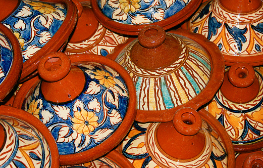 Tall stack of colorful painted clay tajine pots at a Moroccan market.