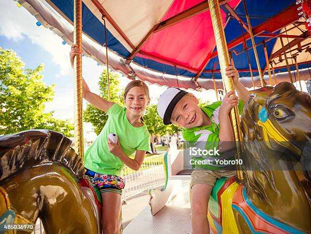 Cute Kids Having Fun Riding On A Colorful Carnival Carousel Stock Photo - Download Image Now