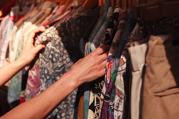 frau suchen kleidung im markt - straßenmarkt stock-fotos und bilder