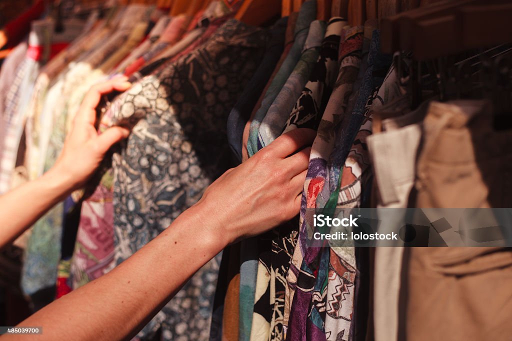 Woman browsing clothes at market A young woman is browsing a rail of clothes at a street market Thrift Store Stock Photo