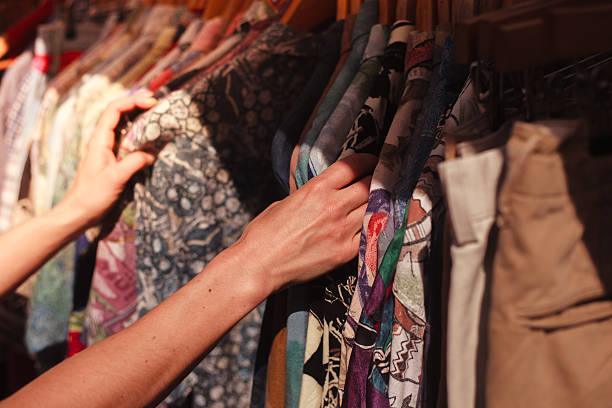 Woman browsing clothes at market A young woman is browsing a rail of clothes at a street market london fashion stock pictures, royalty-free photos & images