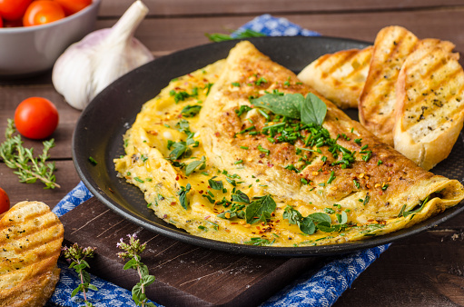 Herb omelette with chives and oregano sprinkled with chili flakes, garlic panini toasts