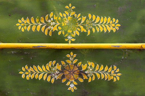 The yellow floral design on the back of a vintage green rickshaw in India (close-up).
