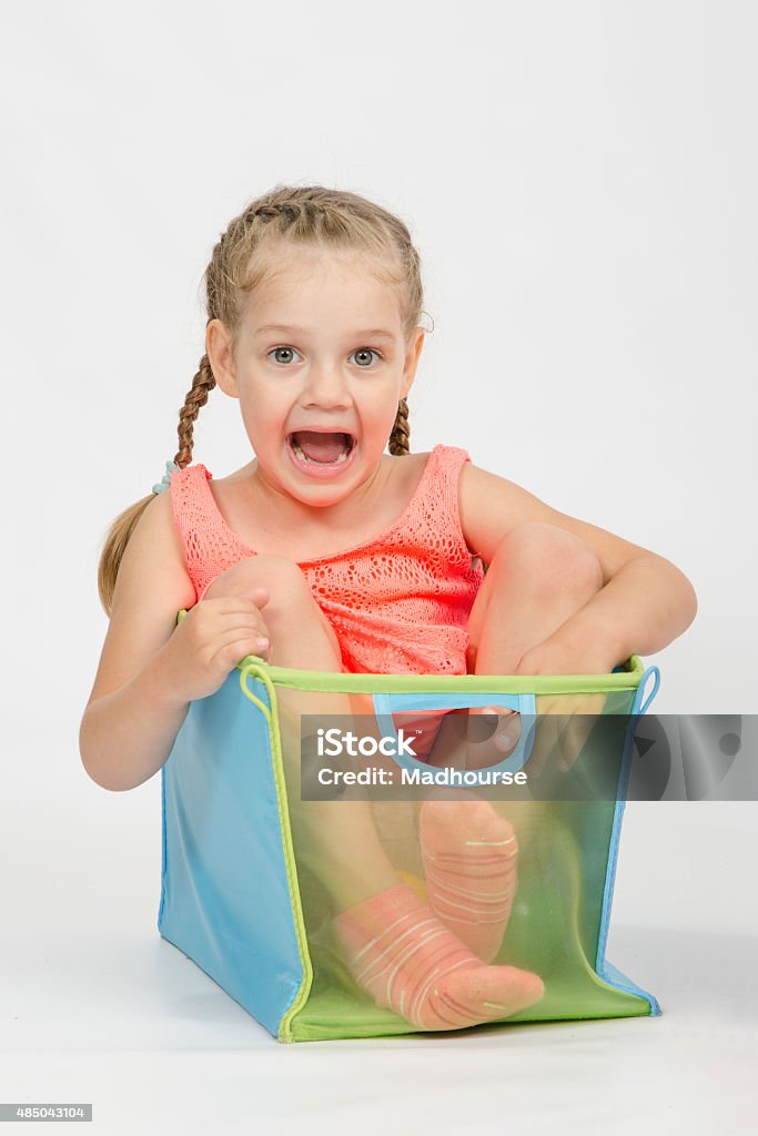 Happy girl in a box for toys Four-year girl playing in a European-style cubes, isolated on a light background 2015 Stock Photo
