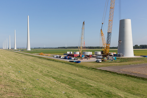 Dutch farmland with construction site of enormous new wind turbines