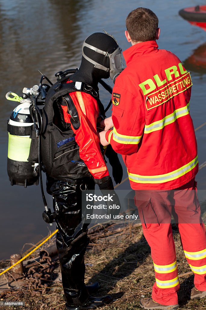 DLRG Einsatztaucher - Rescue diver Wiesbaden, Germany - February 4, 2012: A member of german DLRG (Deutsche Lebensrettungsgesellschaft) assists and checks the equipment of a fully equipped rescue diver shortly after his mission in River Rhine, Germany. 2015 Stock Photo