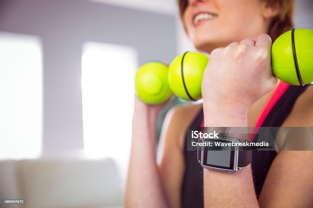 Fit woman lifting dumbbell sitting on ball Fit woman lifting dumbbell sitting on ball at home in the living-room 18-19 Years Stock Photo