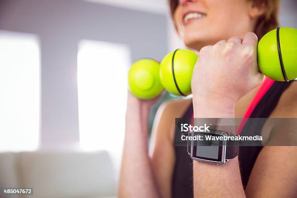 Fit Woman Lifting Dumbbell Sitting On Ball Stock Photo - Download Image Now - 18-19 Years, 2015, Adult