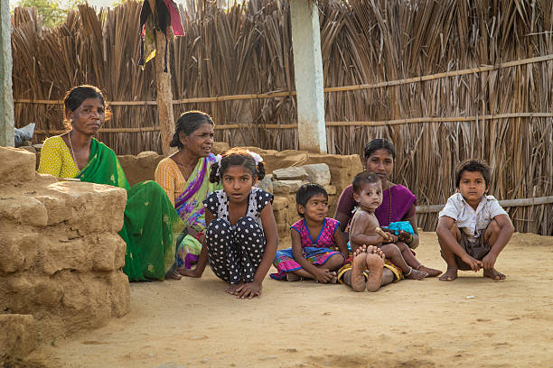 Indian family Hampi, India - January 31, 2015: Rural indian family sitting on ground in evening shade in home courtyard. baby squatting stock pictures, royalty-free photos & images