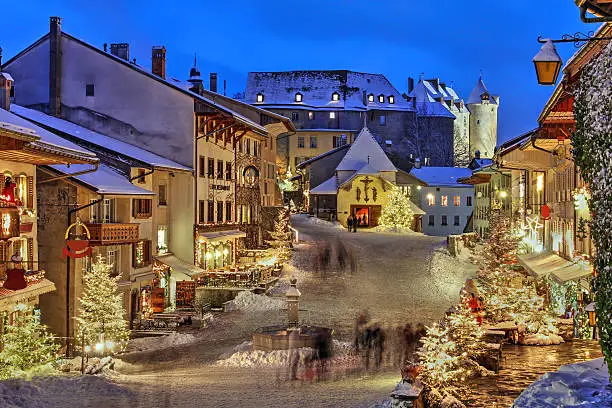 Winter (Christmas) in the medieval town of Gruyeres, Fribourg canton, Switzerland. In the background looming over is the Chateau de Gruyere.