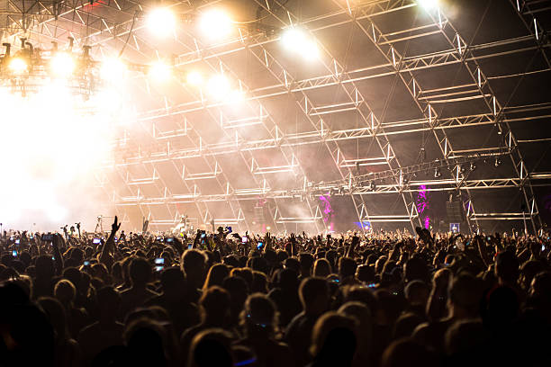 istock Large Concert Crowd Hands In Air With Light Effects 485051436