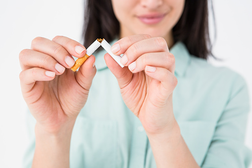 Smiling woman snapping cigarette in half on white background