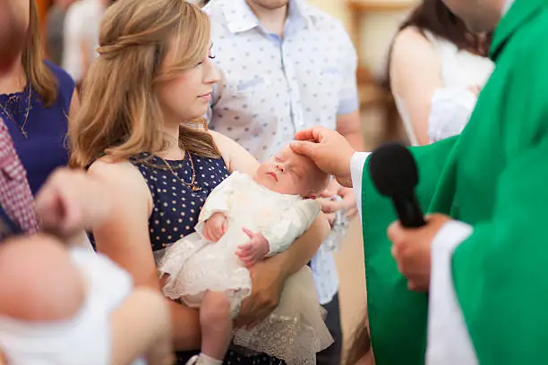 Mother hold little baby on ceremony of child christening in church