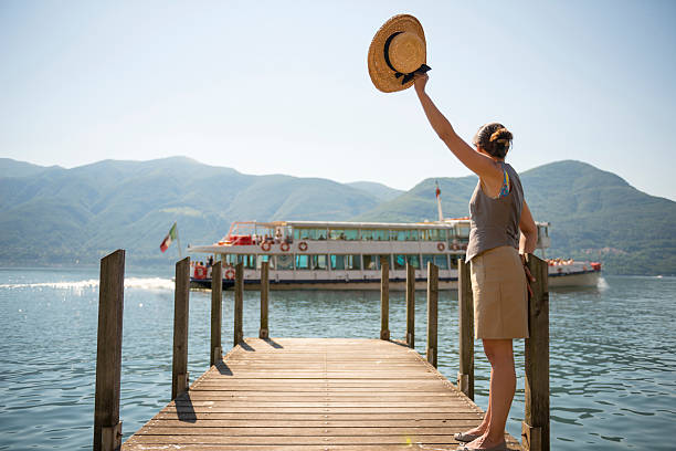 Woman waves to passing boat from pier, Lake Maggiore