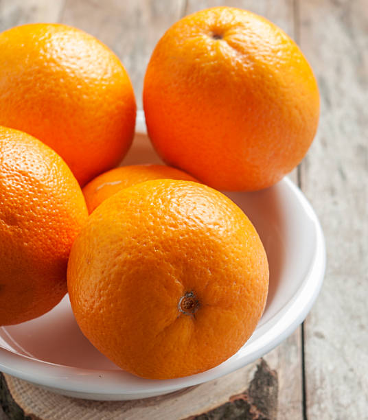 istock orange in white plate on wooden background 485060888