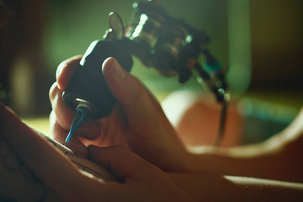 Tattoo master tattooing on the a girl arm.