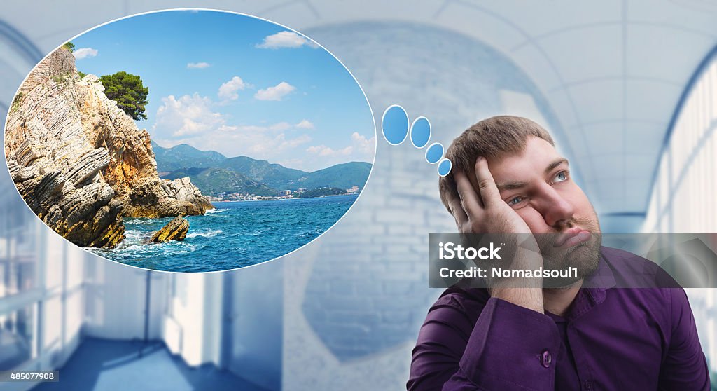 Sad man dreaming about vacation Sad man dreaming about his summer vacation at work 2015 Stock Photo