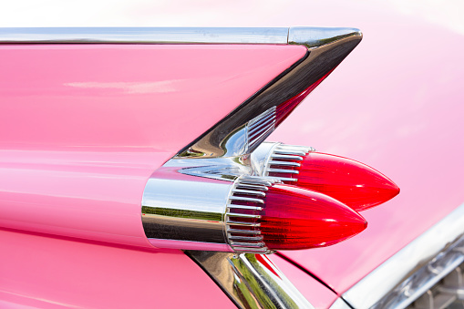 Geiselwind, Germany - June 20, 2015: Tail fin and rear lights of a 1959 pink Cadillac Coupe de Ville classic car at a vintage American car meeting. Cadillac Motor Car Division, is a division of U.S.-based General Motors.