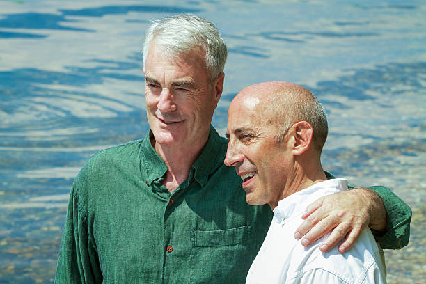 Senior Gay Male Couple at Seashore, Pensive and Planning Future stock photo