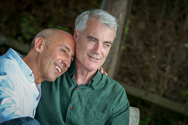 Senior Gay Male Couple at Seashore, Pensive and Planning Future stock photo