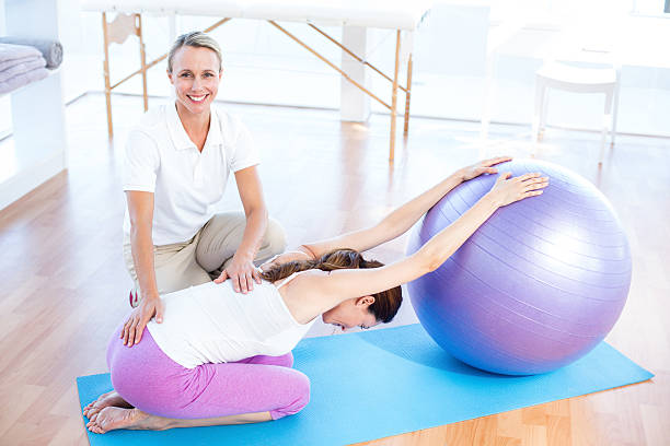 istock Trainer helping woman with exercise ball 485107644