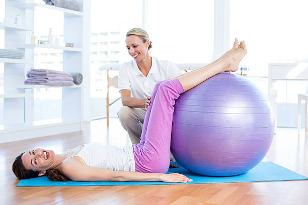 istock Trainer helping woman with exercise ball 485107660